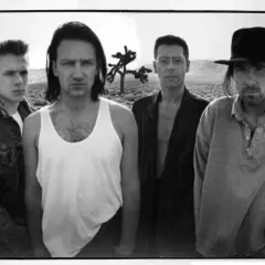 I membri degli U2 posano in un paesaggio desertico, con un Joshua Tree sullo sfondo.