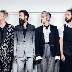 I membri dei Bluvertigo posano in abiti eleganti e audaci, pronti per un nuovo capitolo musicale.