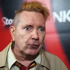 John Lydon, iconico cantante dei Sex Pistols, con un'espressione sorpresa e i capelli biondi spettinati.