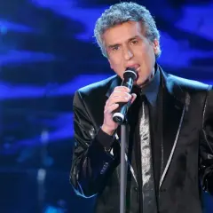 Toto Cutugno canta sul palco, con la sua voce inconfondibile che riempie l'aria, ricordando le sue indimenticabili canzoni.