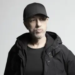 Uomo con cappellino e giacca nera, pensieroso. Potrebbe essere il momento di ascoltare le sue canzoni di Neffa.