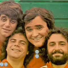 I gatti di Vicolo Miracoli sorridono alla telecamera, un gruppo di amici con capelli mossi e barbe folte.