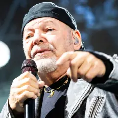 Gerardina trovato, ma non ho più la mia città. Un uomo con berretto nero e giacca di pelle canta al microfono, puntando il dito verso l'esterno.