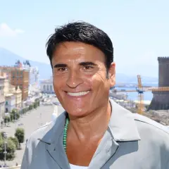 Sorriso di un cantante italiano con Napoli sullo sfondo.