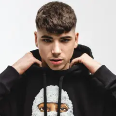 Giovane rapper italiano con un taglio di capelli alla moda, indossa una felpa nera con un disegno artistico.
