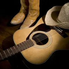 Stivali da cowboy, cappello di paglia e chitarra acustica, pronti per suonare le più belle canzoni country famose.