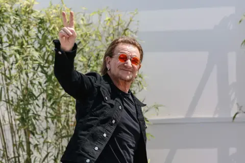 Bono con occhiali arancioni fa il segno di vittoria, forse un anticipo del nuovo u2 new album.