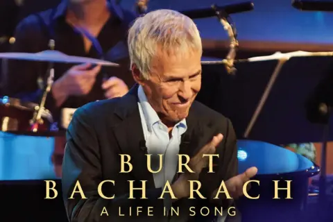 Burt Bacharach, leggendario compositore, sorride sul palco, celebrando le sue indimenticabili canzoni.