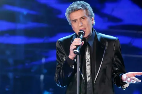 Toto Cutugno canta sul palco, con la sua voce inconfondibile che riempie l'aria, ricordando le sue indimenticabili canzoni.
