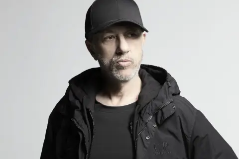 Uomo con cappellino e giacca nera, pensieroso. Potrebbe essere il momento di ascoltare le sue canzoni di Neffa.