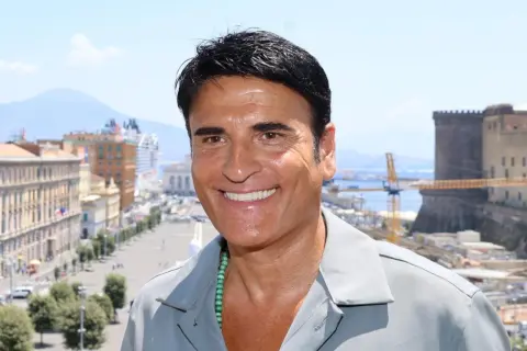 Sorriso di un cantante italiano con Napoli sullo sfondo.