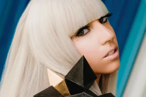 Lady Gaga con i suoi iconici capelli biondi e un look audace, ricorda la sua prima canzone.