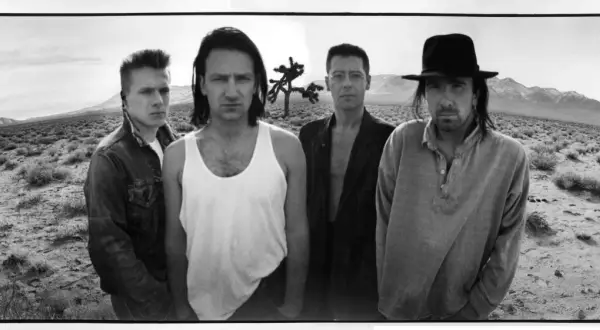 I membri degli U2 posano in un paesaggio desertico, con un Joshua Tree sullo sfondo.