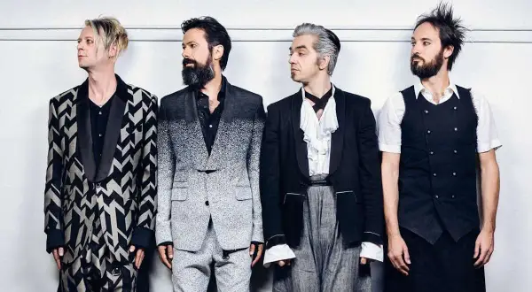 I membri dei Bluvertigo posano in abiti eleganti e audaci, pronti per un nuovo capitolo musicale.