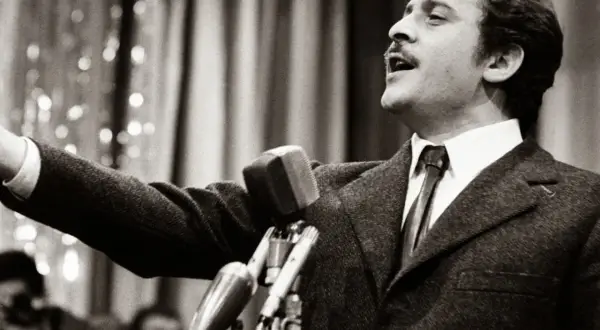 Domenico Modugno, originario di Polignano a Mare, canta con passione al microfono, con il braccio teso.