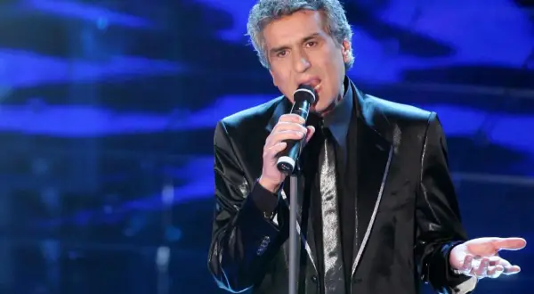 Toto Cutugno canta sul palco, con la sua voce inconfondibile che riempie l'aria, ricordando le sue indimenticabili canzoni.