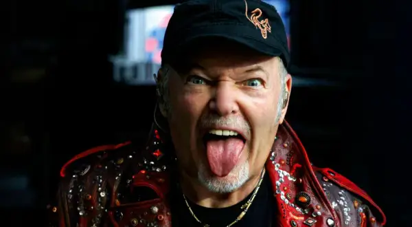 Vasco Rossi, con la lingua fuori e un'espressione grintosa, indossa una giacca borchiata. Chissà quante canzoni ha fatto Vasco Rossi per arrivare a tanta energia!