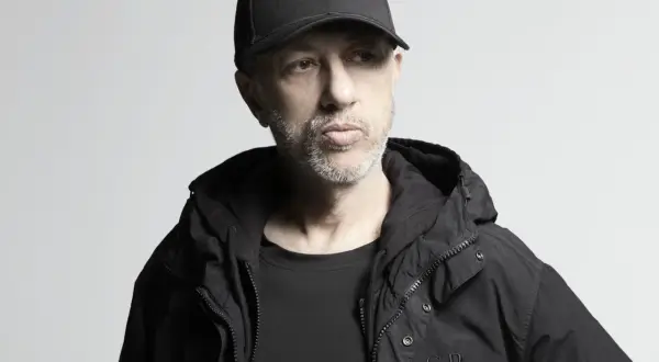 Uomo con cappellino e giacca nera, pensieroso. Potrebbe essere il momento di ascoltare le sue canzoni di Neffa.