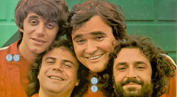 I gatti di Vicolo Miracoli sorridono alla telecamera, un gruppo di amici con capelli mossi e barbe folte.