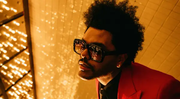 The Weeknd, con occhiali oversize e giacca rossa, pronto per le avventure after hours.