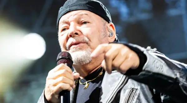 Gerardina trovato, ma non ho più la mia città. Un uomo con berretto nero e giacca di pelle canta al microfono, puntando il dito verso l'esterno.