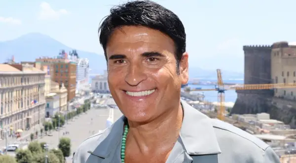 Sorriso di un cantante italiano con Napoli sullo sfondo.