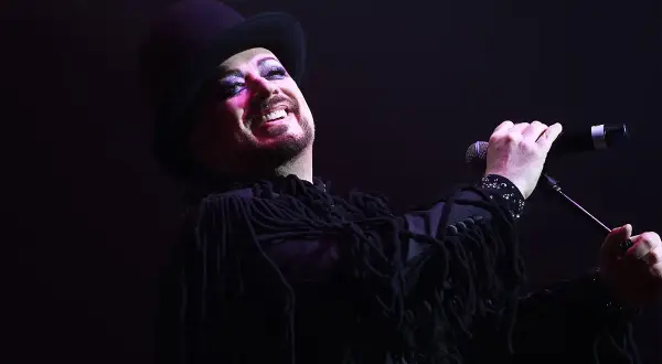 Boy George, icona dei Culture Club, canta con trucco audace e cappello a cilindro.