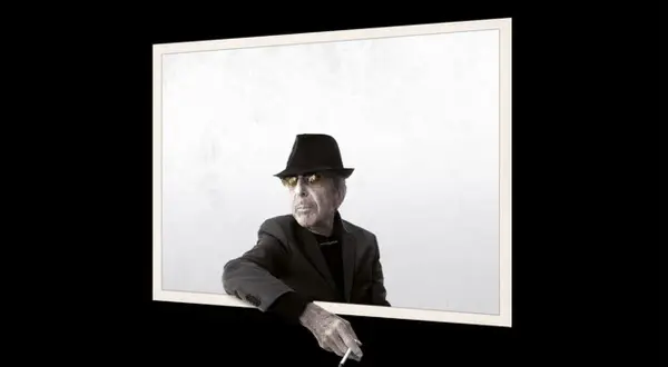 Uomo con cappello e occhiali da sole, sigaretta in mano, sembra volere un'atmosfera più scura.