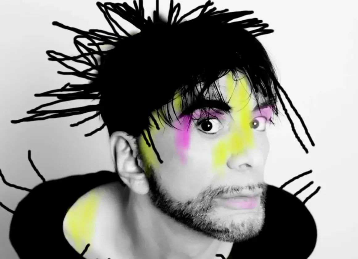 Ritratto di Ivan Cattaneo con capelli neri a punta, trucco colorato e barba. Le sue canzoni sono uniche.