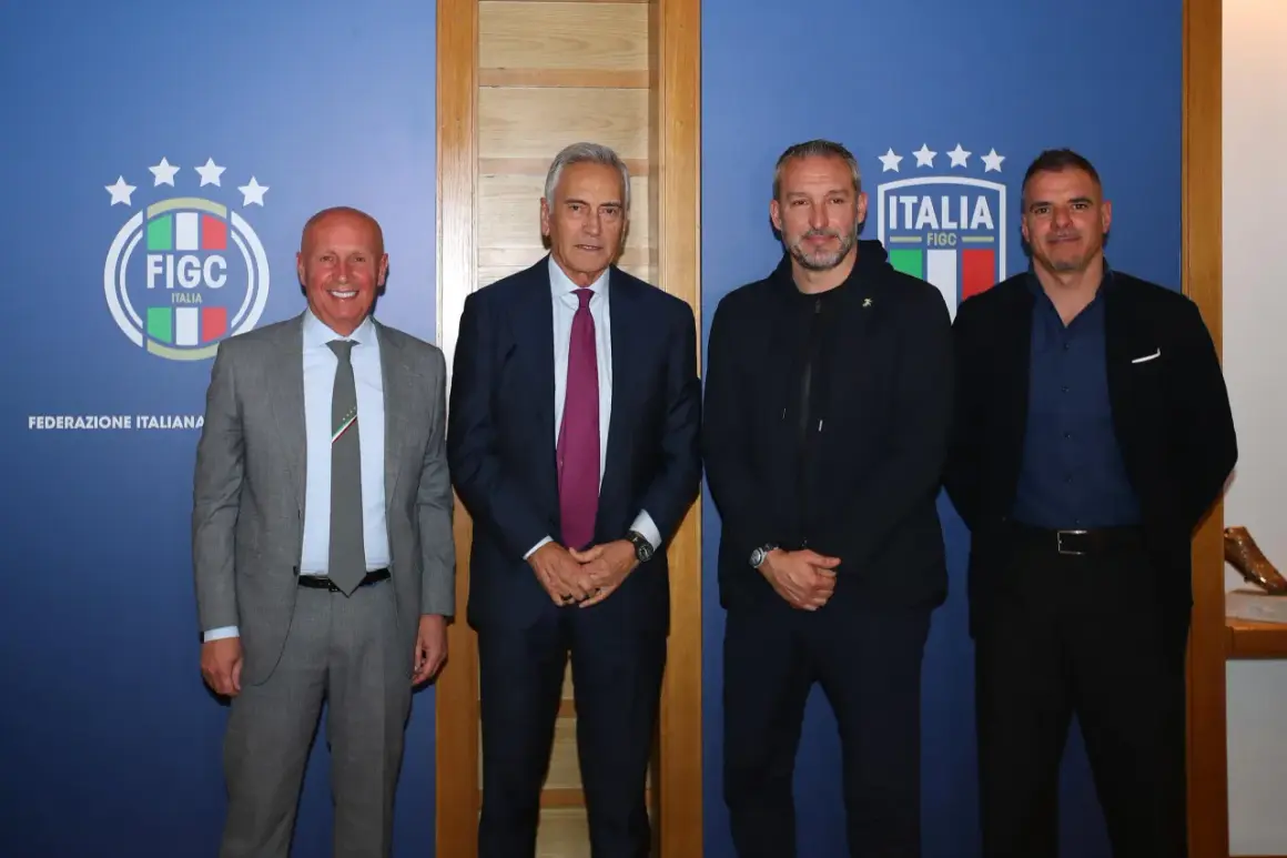 Quattro uomini in posa davanti a uno sfondo blu con il logo FIGC. Nessuno sembra un "dead can dance", ma tutti sono vestiti elegantemente.