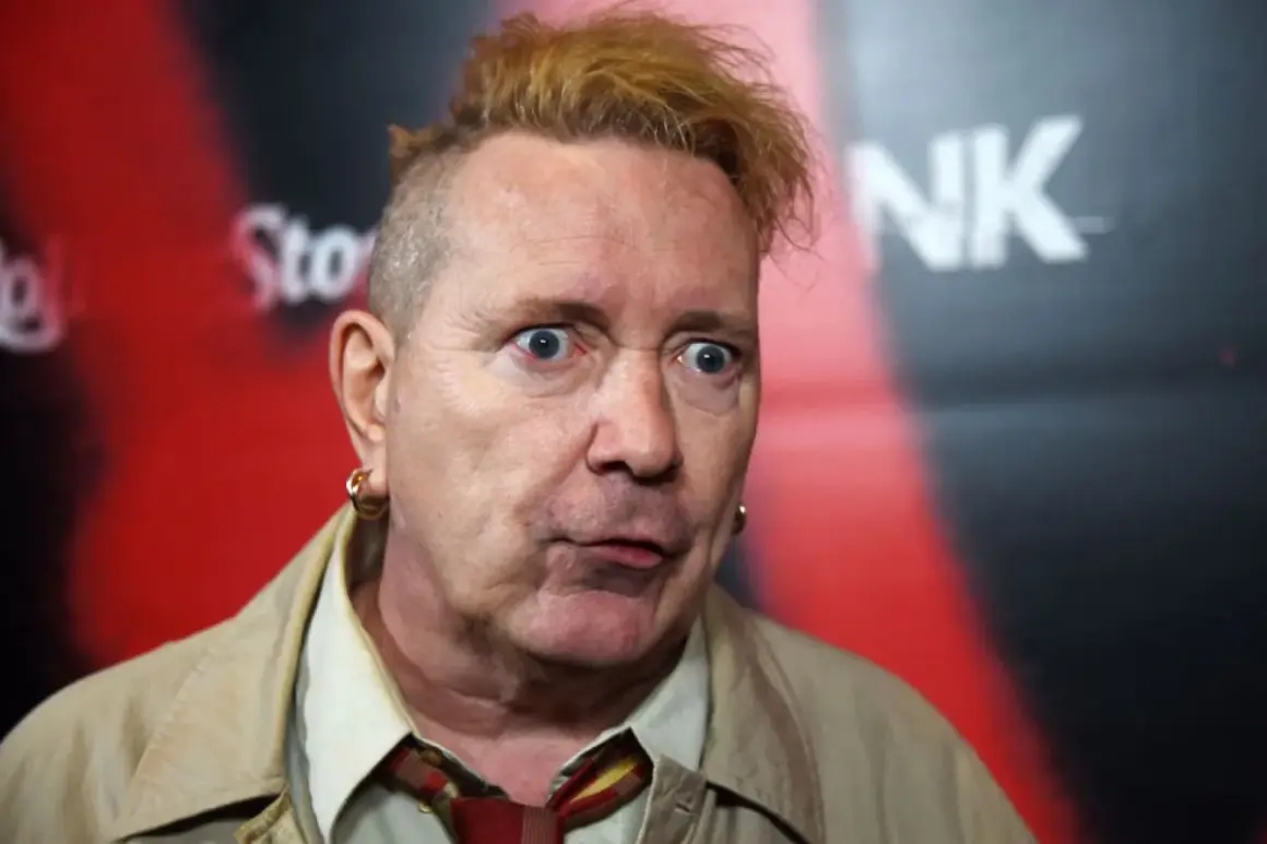 John Lydon, iconico cantante dei Sex Pistols, con un'espressione sorpresa e i capelli biondi spettinati.