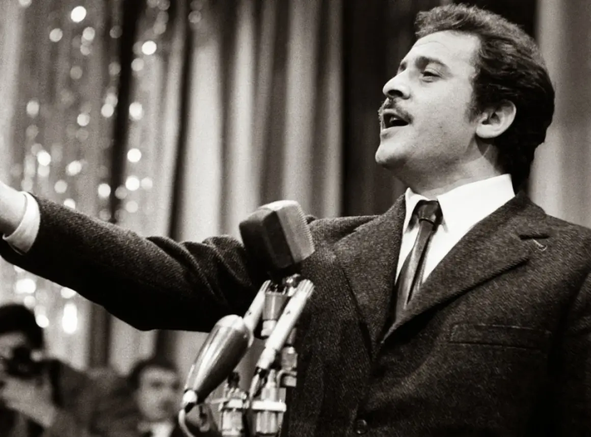 Domenico Modugno, originario di Polignano a Mare, canta con passione al microfono, con il braccio teso.
