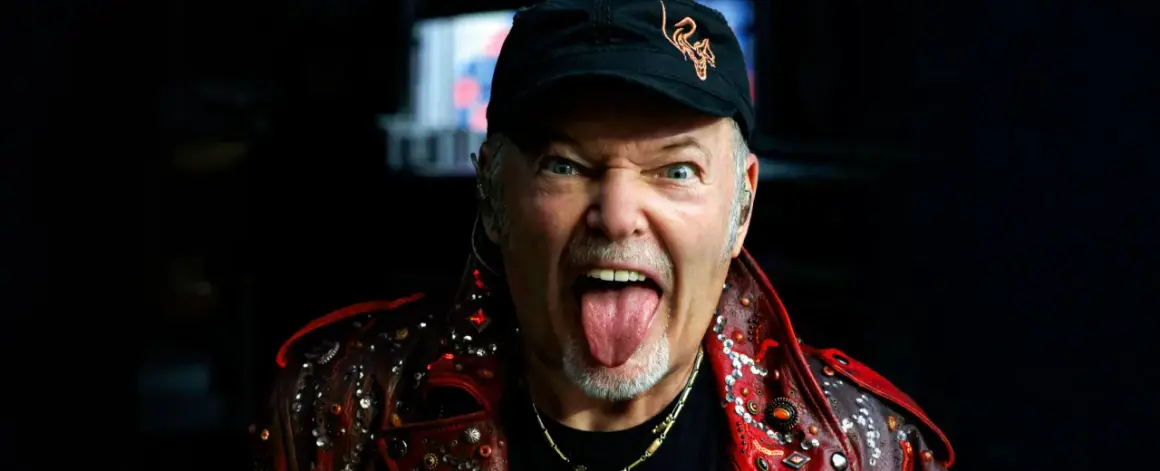 Vasco Rossi, con la lingua fuori e un'espressione grintosa, indossa una giacca borchiata. Chissà quante canzoni ha fatto Vasco Rossi per arrivare a tanta energia!