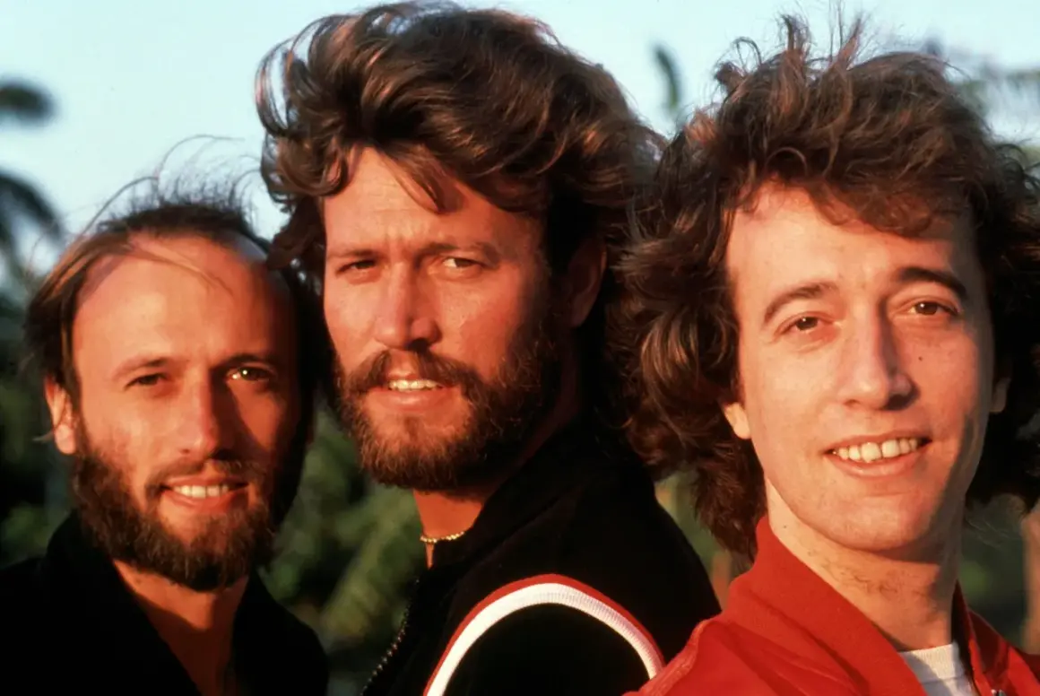 I tre fratelli Gibb dei Bee Gees, con i loro iconici capelli e sorrisi, sembrano dire "run to me" con la loro musica.