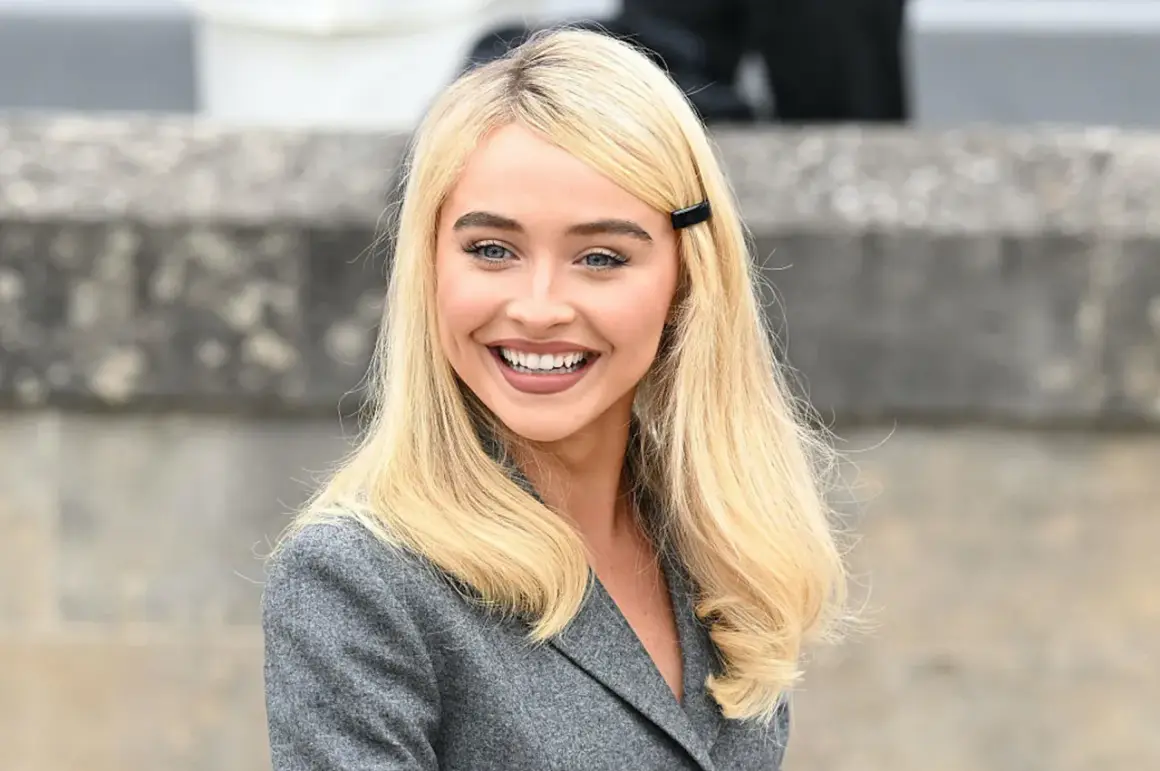 Sabrina Carpenter sorride, con i capelli biondi e un blazer grigio. Ricorda i suoi film e programmi TV.