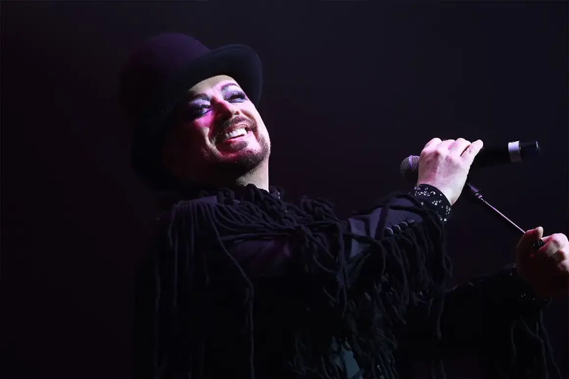 Boy George, icona dei Culture Club, canta con trucco audace e cappello a cilindro.