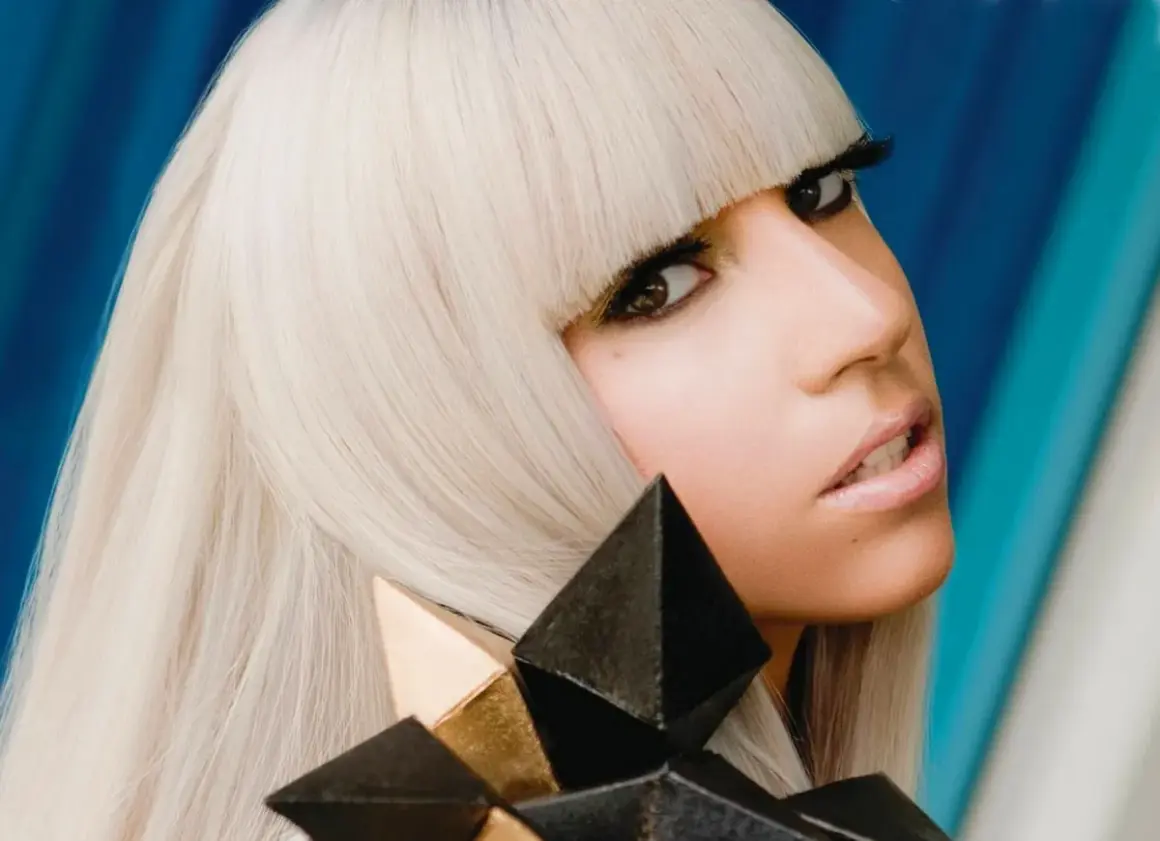 Lady Gaga con i suoi iconici capelli biondi e un look audace, ricorda la sua prima canzone.