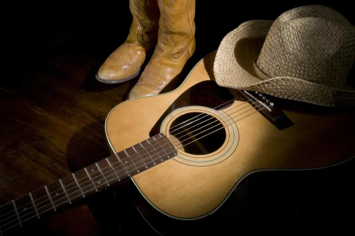 Stivali da cowboy, cappello di paglia e chitarra acustica, pronti per suonare le più belle canzoni country famose.