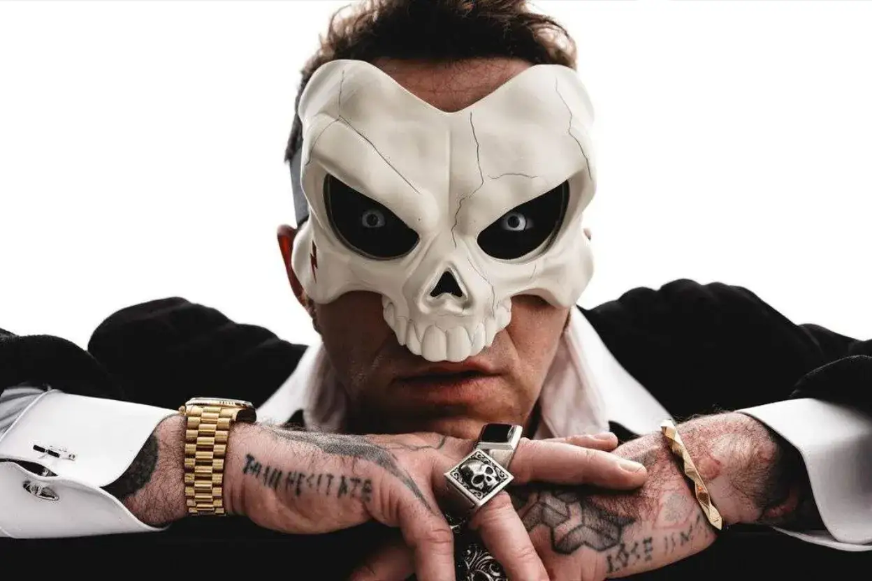 Salmo indossa una maschera da teschio, pronto per il suo nuovo album. Bracciali d'oro e anelli completano il look.