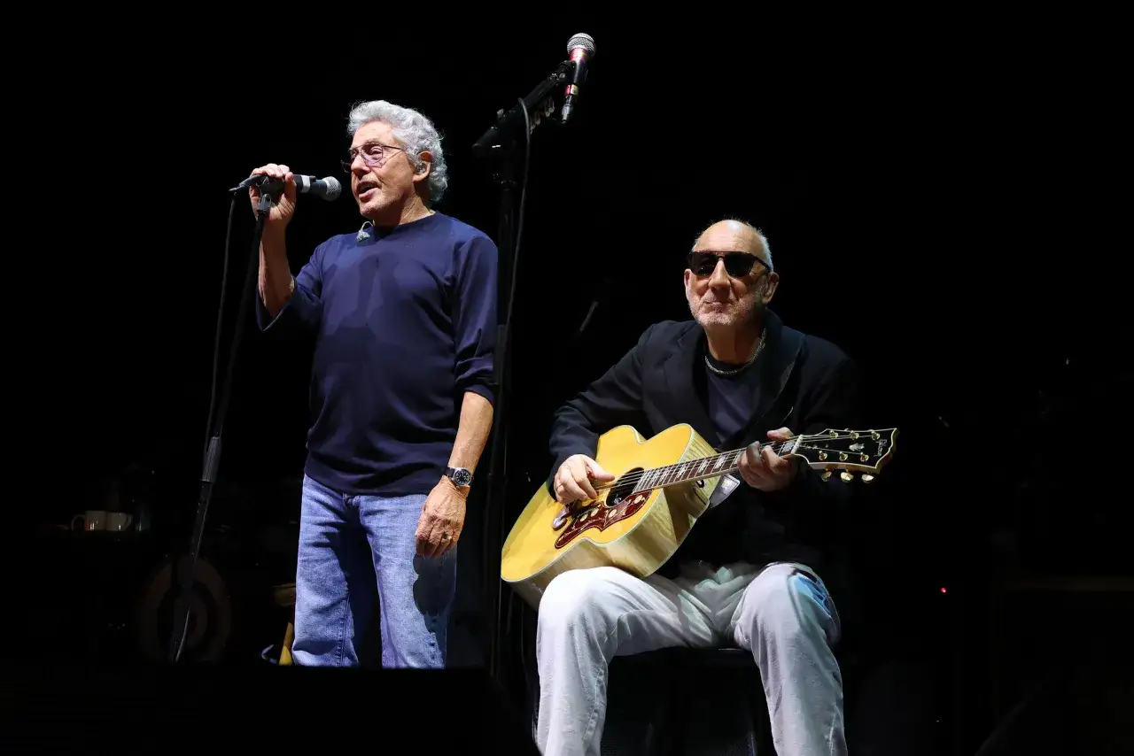 Roger Daltrey, the iconic cantante of The Who, canta al microfono mentre Pete Townshend suona la chitarra acustica sul palco.