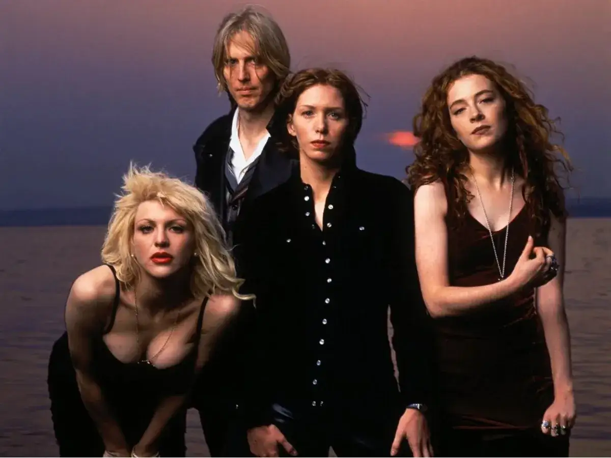 Il gruppo musicale Hole posa al tramonto. Courtney Love in primo piano, con gli altri membri sullo sfondo.