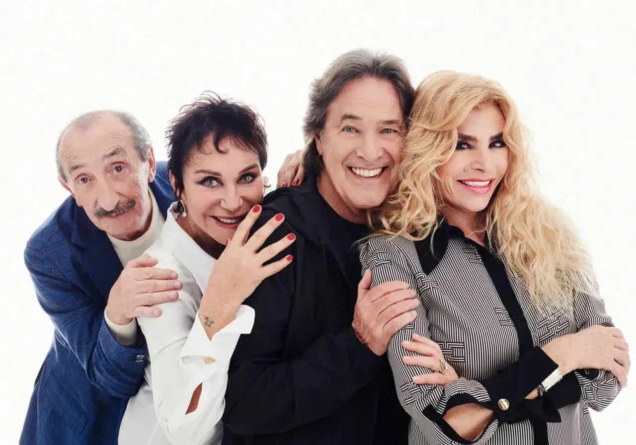 Quattro amici, ricchi e poveri anni, sorridono abbracciati.