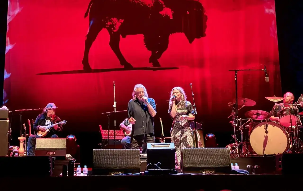 Robert Plant, la sua saving grace, canta sul palco con una donna, sullo sfondo un bisonte rosso.
