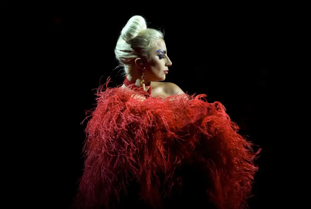 Lady Gaga, con un'acconciatura voluminosa e un abito di piume rosse, evoca l'audacia del suo inizio carriera.