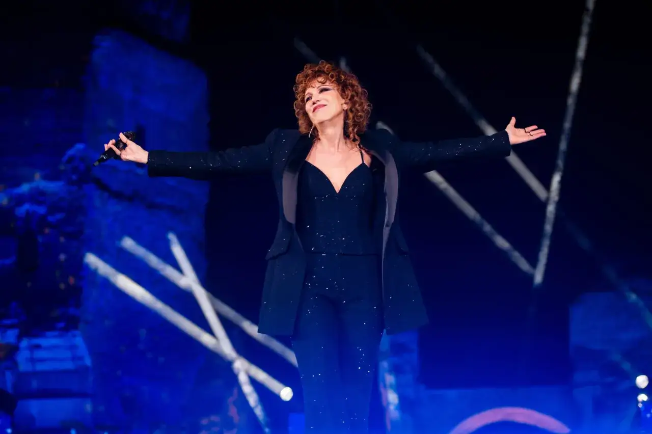 Fiorella Mannoia, con braccia aperte e microfono in mano, incanta il pubblico con le sue canzoni.