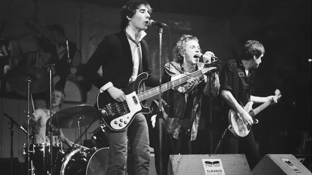 Il cantante dei Sex Pistols, Johnny Rotten, urla al microfono mentre la band suona.