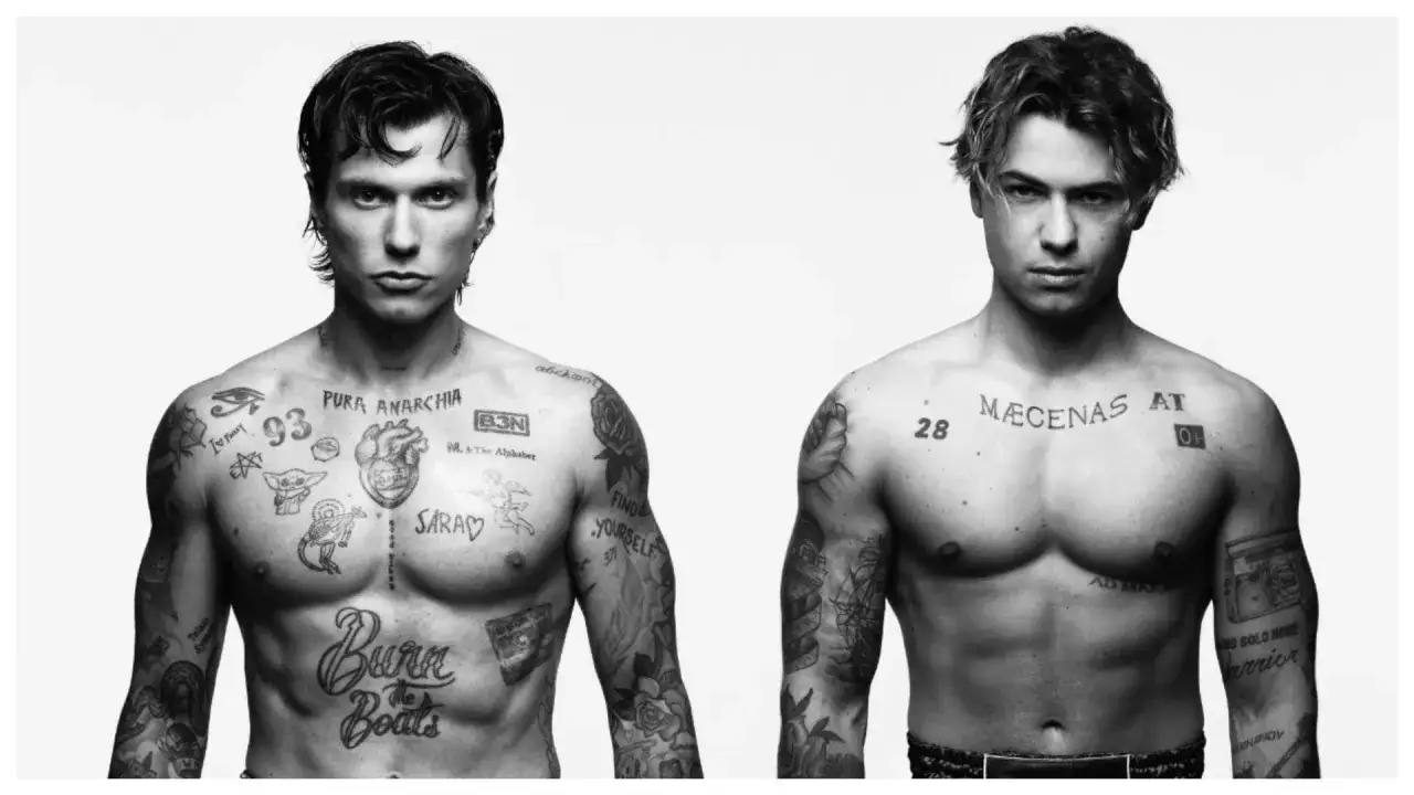 Due giovani uomini con tatuaggi sul petto. Uno ha scritto 