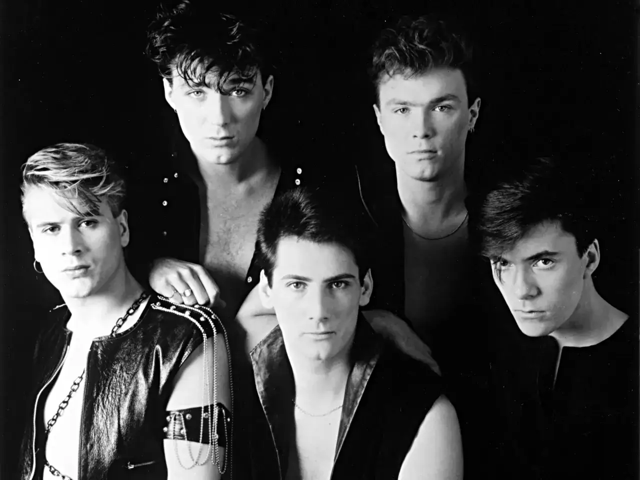 I membri degli Spandau Ballet posano in un ritratto in bianco e nero, con un'espressione intensa e un look audace.