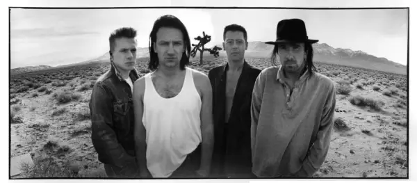 I membri degli U2 posano in un paesaggio desertico, con un Joshua Tree sullo sfondo.