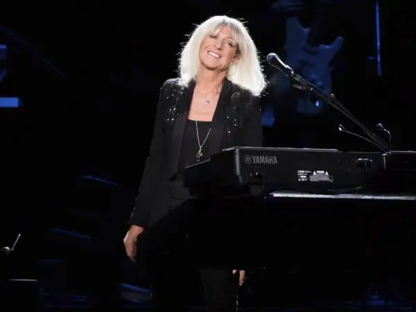 La cantante dei Fleetwood Mac, con i capelli biondi sciolti, sorride dietro una tastiera Yamaha.